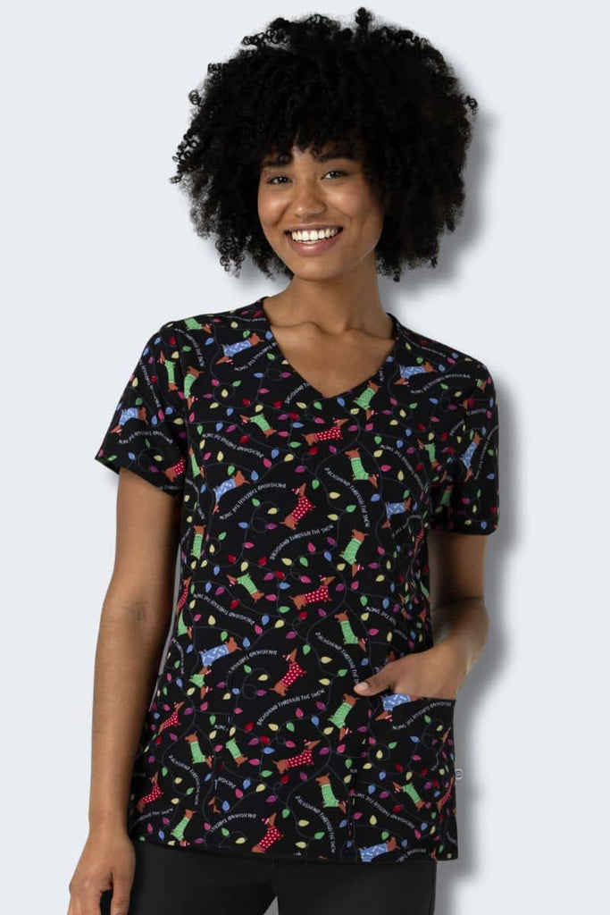 Woman wearing a colorful patterned scrub top against a white background