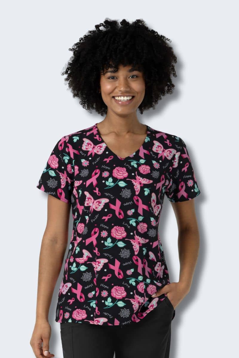Woman wearing a black scrub top with pink ribbon and floral pattern on a white background