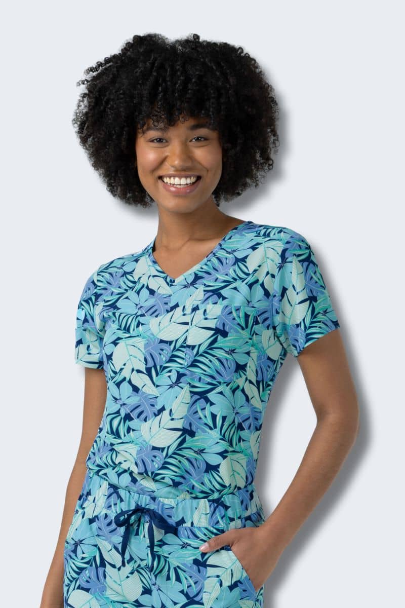 Woman wearing a blue tropical leaf patterned shirt against a light gray background