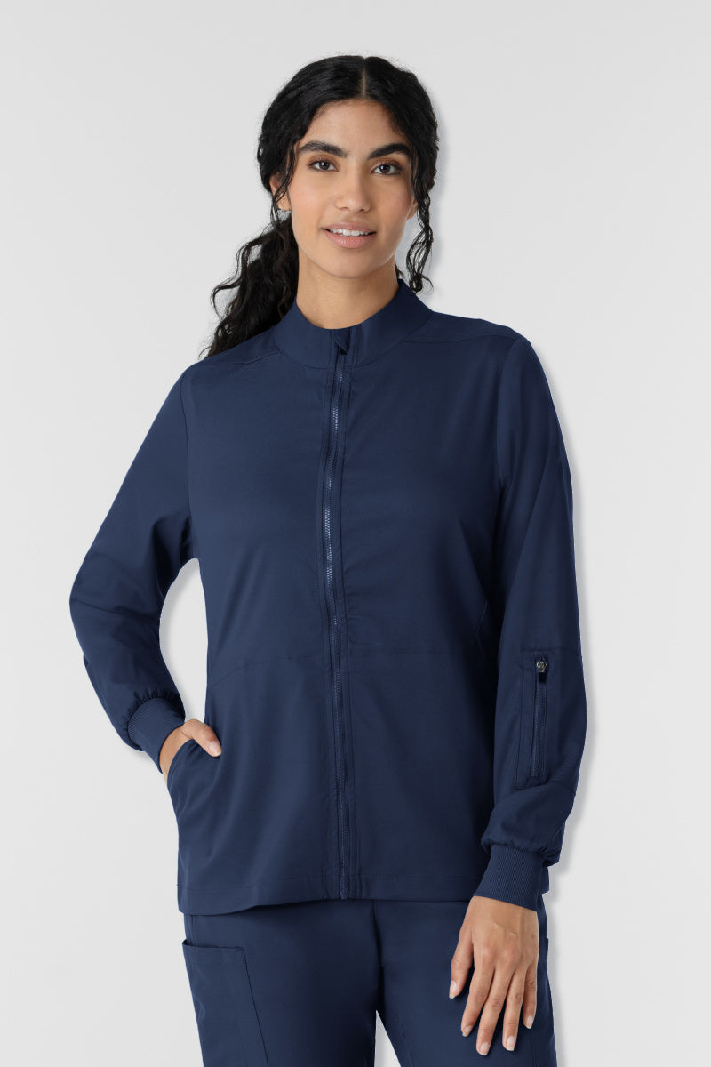 Woman wearing a navy blue jacket and pants on a white background. Wink Boundless scrub jacket