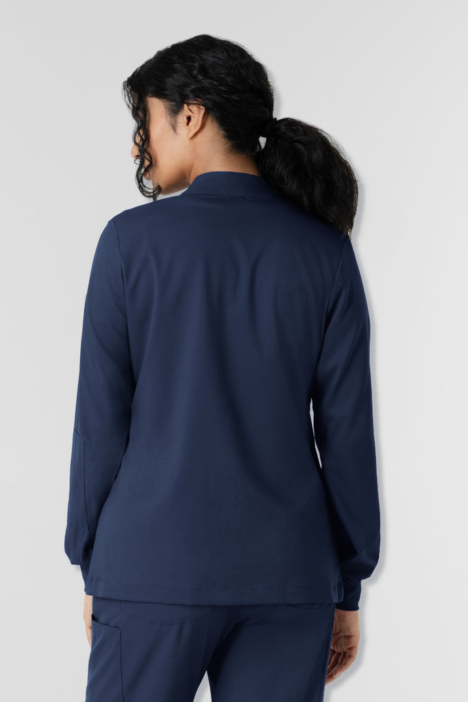 Person wearing a navy blue outfit against a light gray background. Wink Boundless scrub jacket