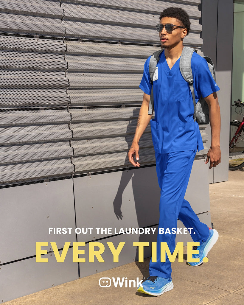 Person in blue scrubs walking outdoors with promotional text overlay. Wink Boundless Men's scrubs