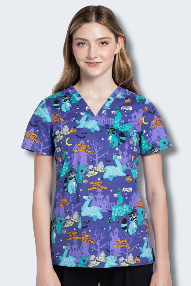 Woman wearing a colorful patterned scrub top on a plain background. CK651 Cherokee Print Alpacalypse