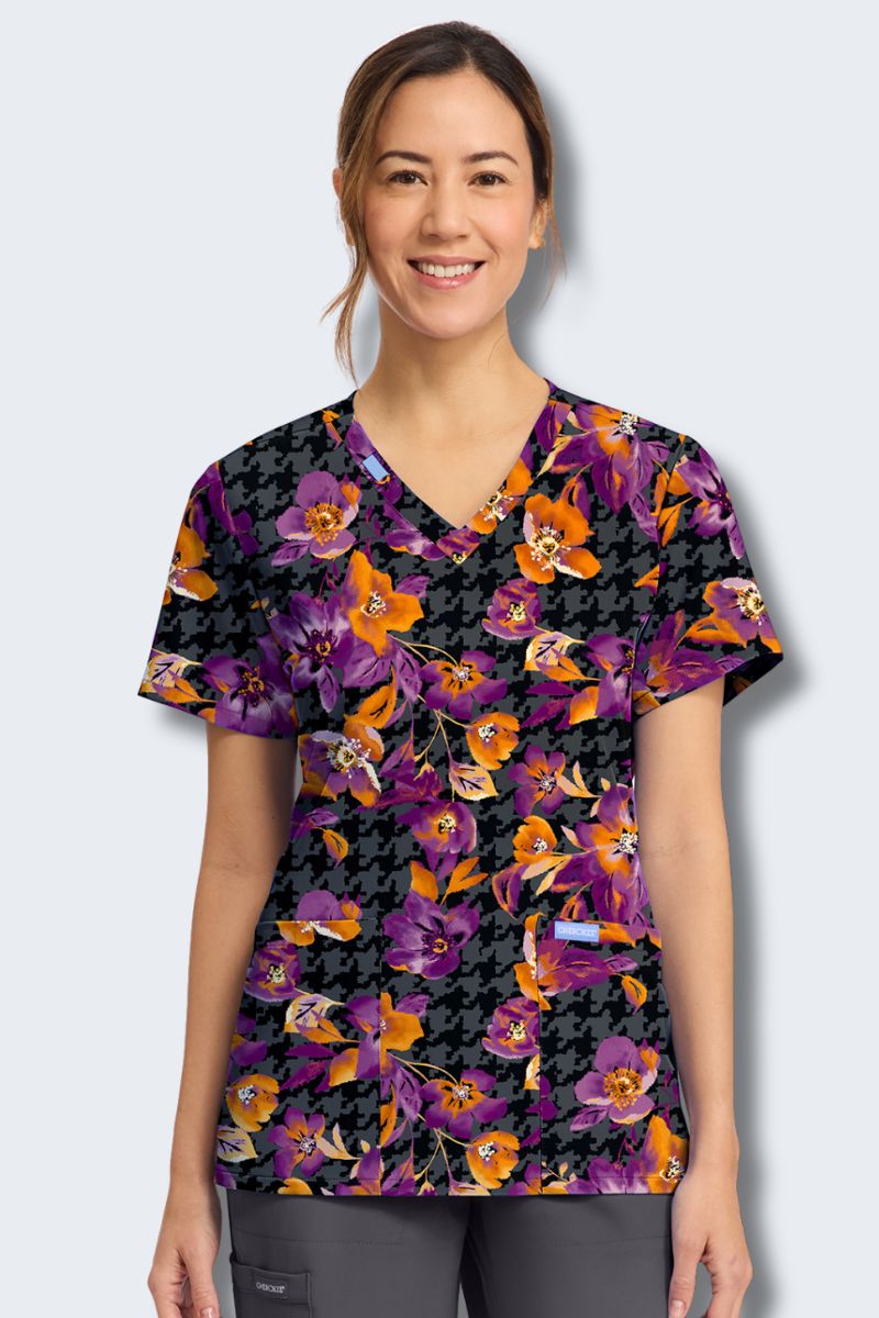 Woman wearing a floral-patterned scrub top on a plain background. Cherokee Prints CK856_VLFL