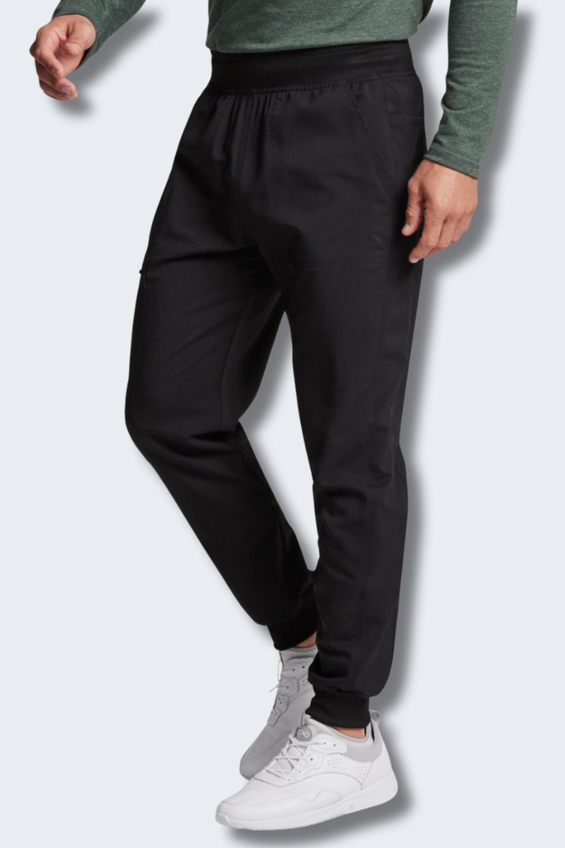 Person wearing black jogger pants and white sneakers on a light gray. background. Dickies DK224