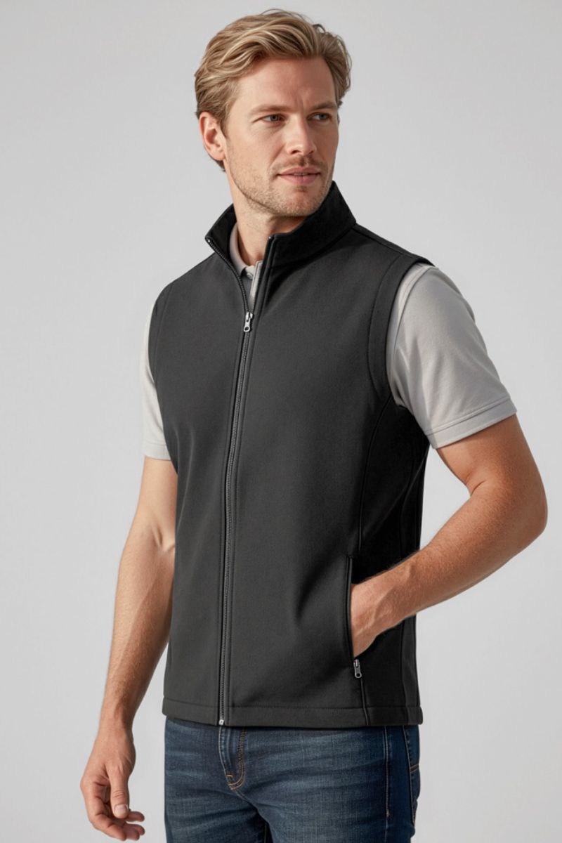 Man wearing a black vest over a light gray shirt on a plain background
