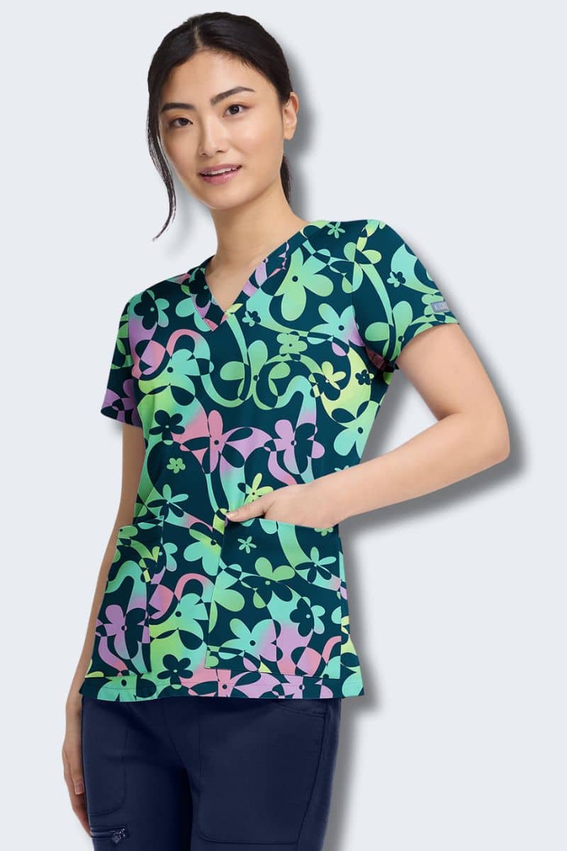 Woman wearing a colorful patterned scrub top on a white background